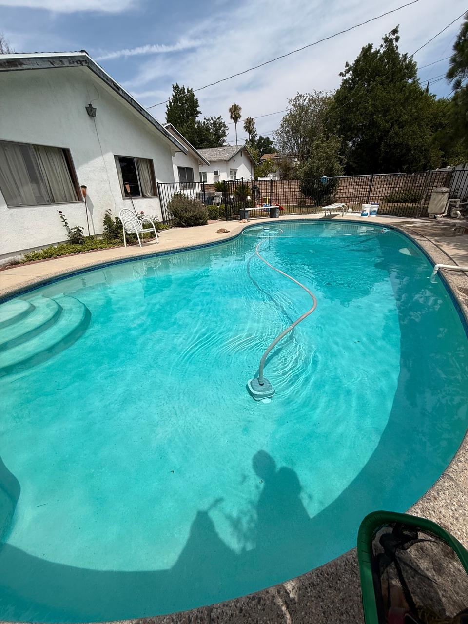 Suction-side pool cleaner running in a clear blue residential pool serviced by KLUG Pool Services